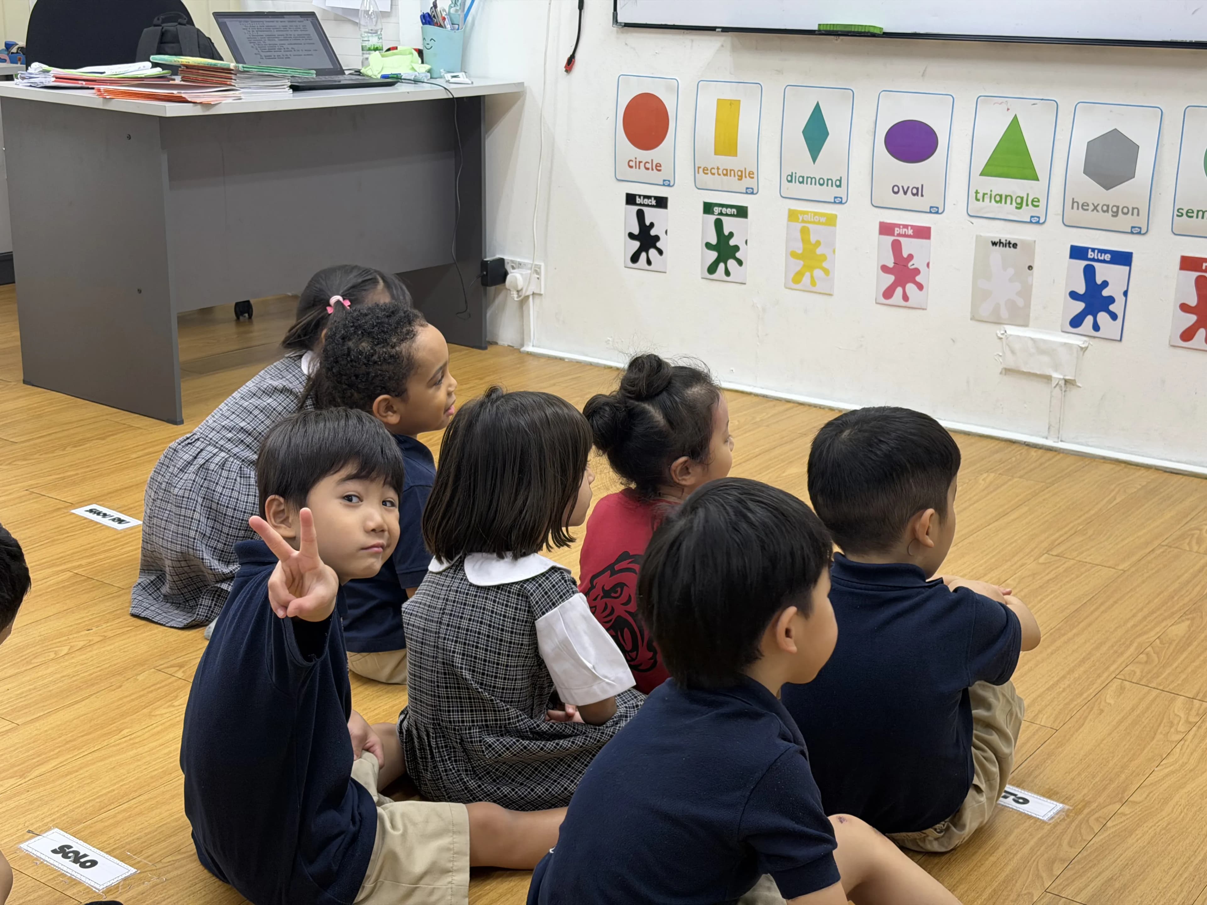 A young child drawing with focused attention in class.